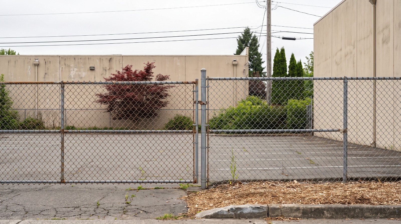 AI-rendered view of the fenced, empty parking lot at 940 San Rafael Avenue in Mountain View, with the light-industrial building behind it, as it looks today