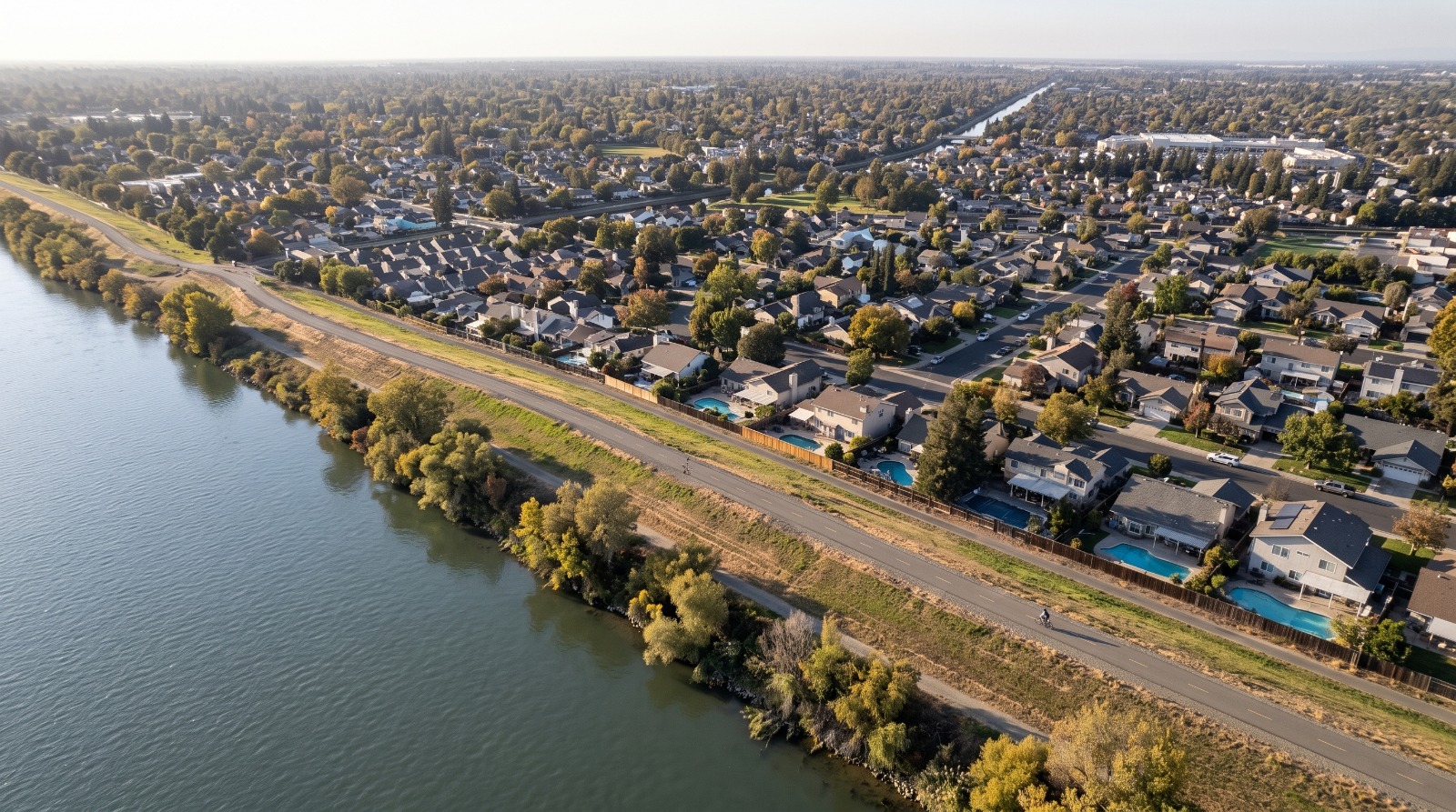AI-rendered oblique aerial view of the Sacramento River east levee along the Pocket neighborhood in Sacramento, with homes below the levee crest