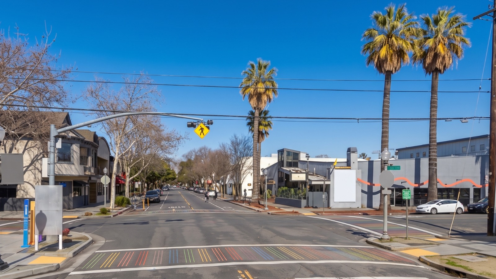AI-rendered view of 20th and K Streets in Sacramento's Lavender Heights under midday sun, with the rainbow crosswalk and palm trees on K Street