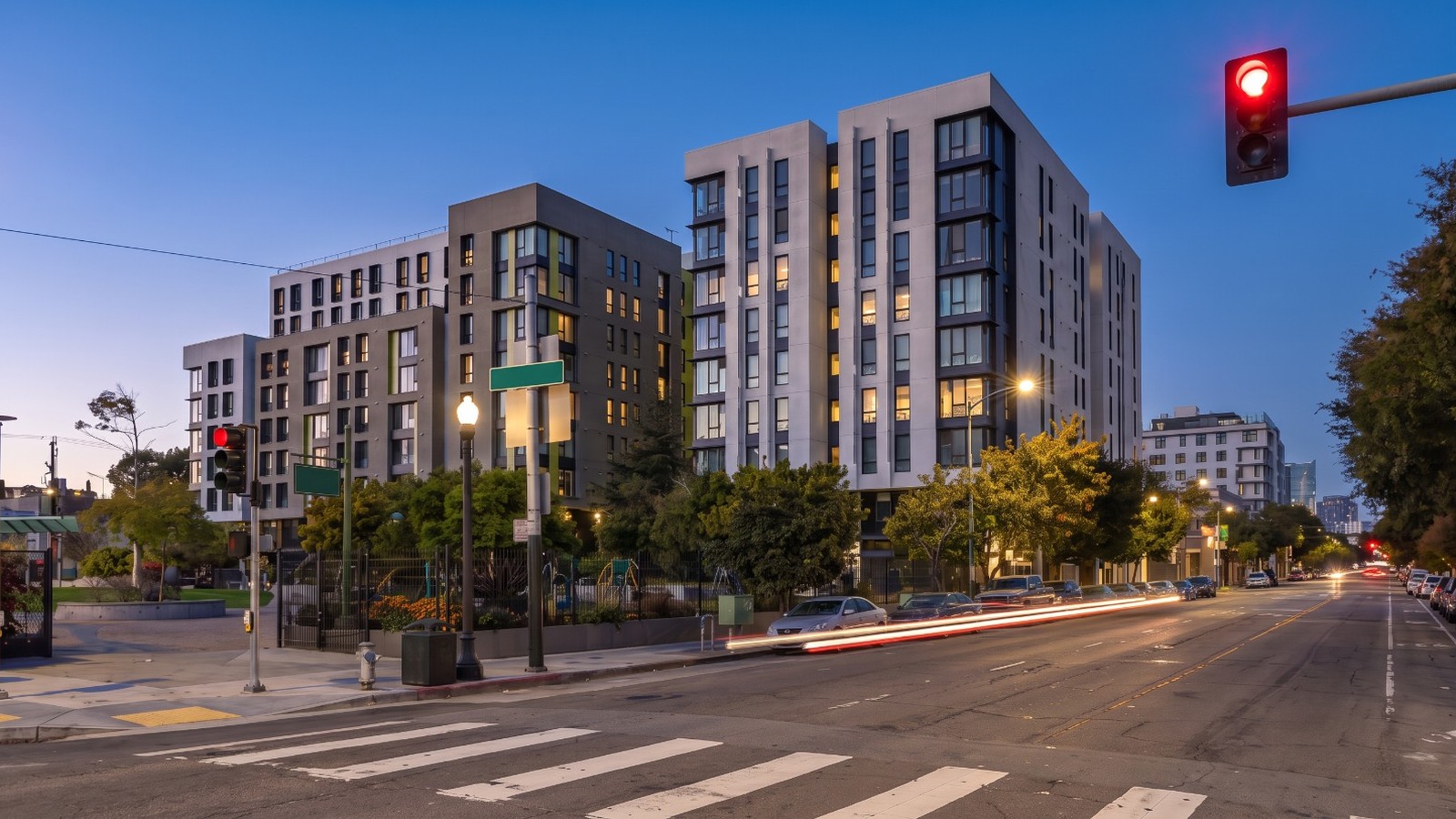AI-rendered blue-hour view of new affordable apartment buildings on Folsom Street at 17th Street in San Francisco's Mission District, beside In Chan Kaajal Park