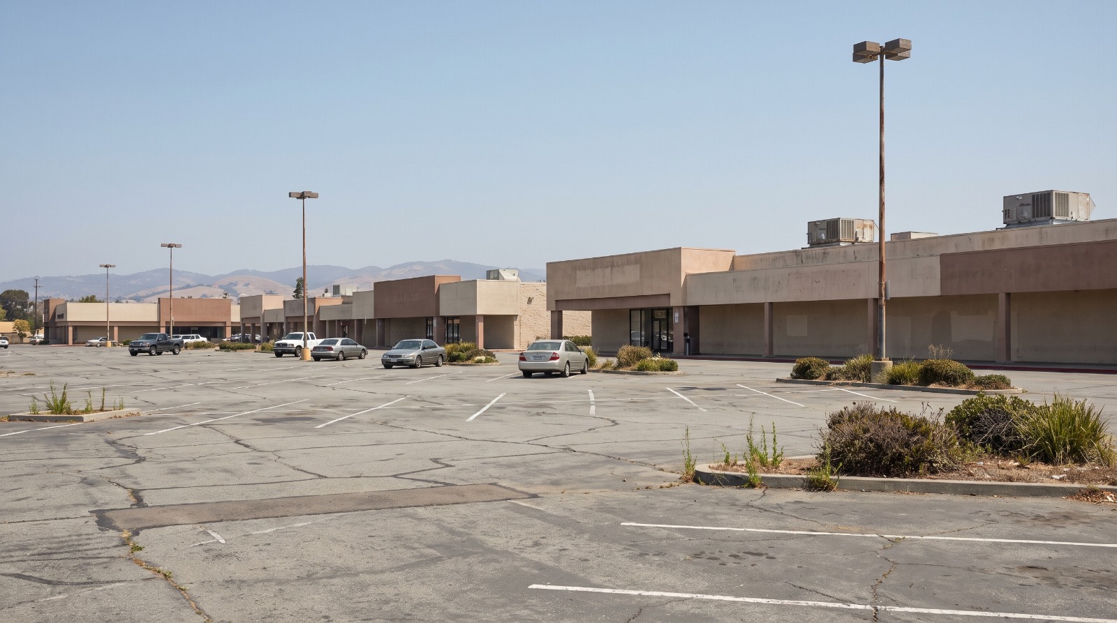 A half-empty shopping center parking lot in San Mateo, California, the kind of site where 847 homes at 690 Concar Drive were just approved.
