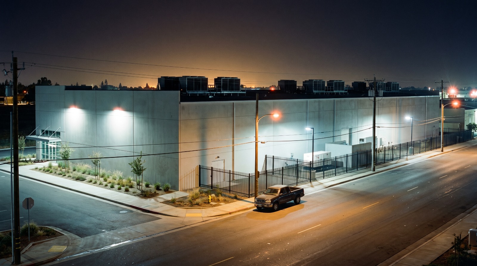 AI-rendered precast concrete data center building at night in McClellan Park, Sacramento County, illustrative of the AK Street campus