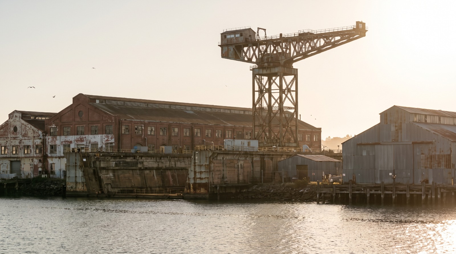 Historic crane and brick shipyard buildings on the Mare Island waterfront in Vallejo, the former Navy shipyard now up for sale