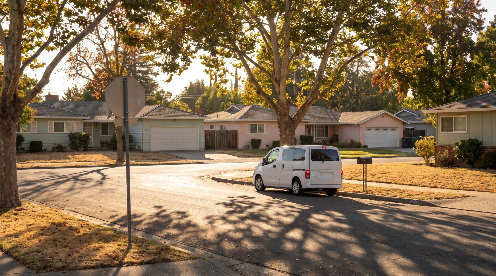 A small white shuttle van pulling up to the curb on a quiet ranch-home street corner in Sunnyvale, the kind of trip Sunnyvale Beam now covers for $3.50.