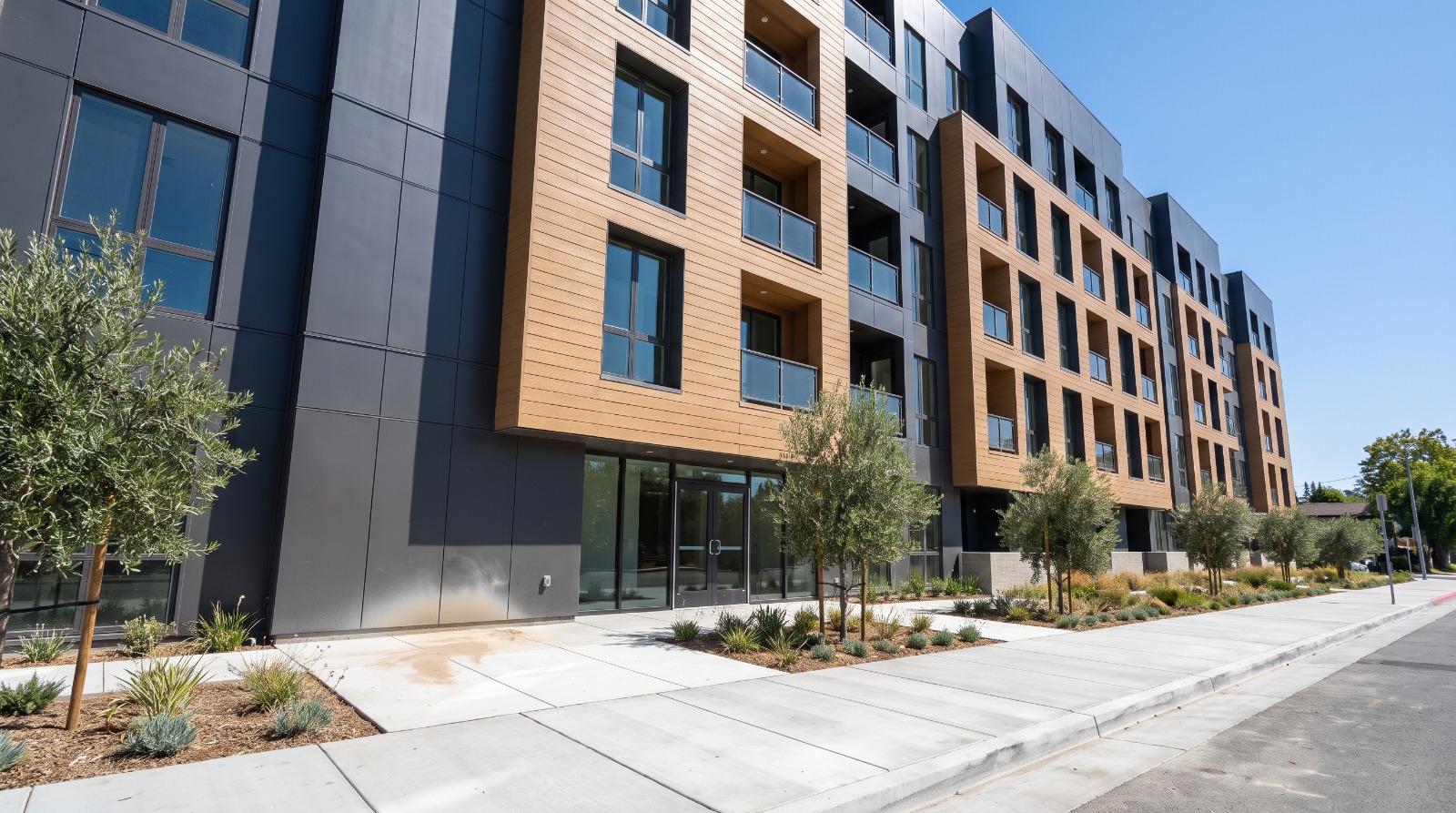 A newly completed seven-story residential building with charcoal and tan panel facade in Mountain View, California