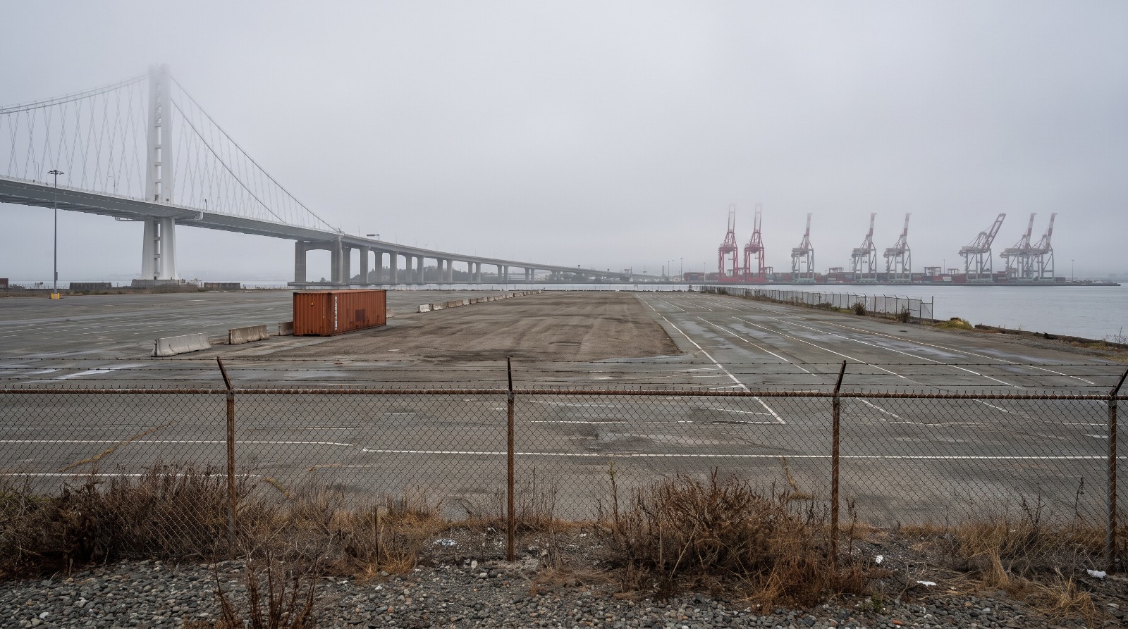AI-rendered view of the empty West Gateway lot at the former Oakland Army Base in fog, with the Bay Bridge and Port of Oakland cranes behind