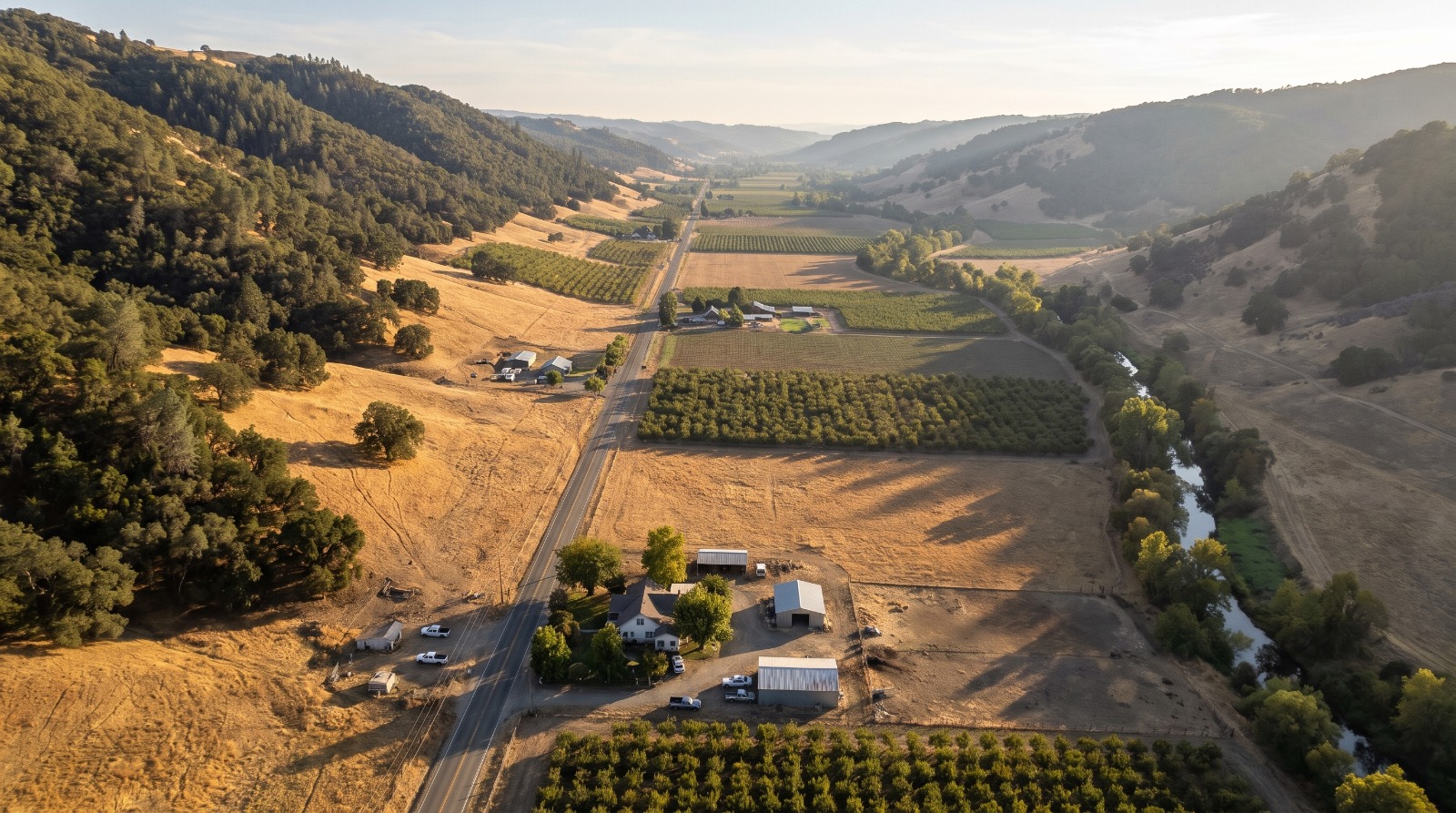 AI-rendered oblique aerial view of the Capay Valley at Guinda in unincorporated Yolo County, with orchards, farmhouses and Cache Creek
