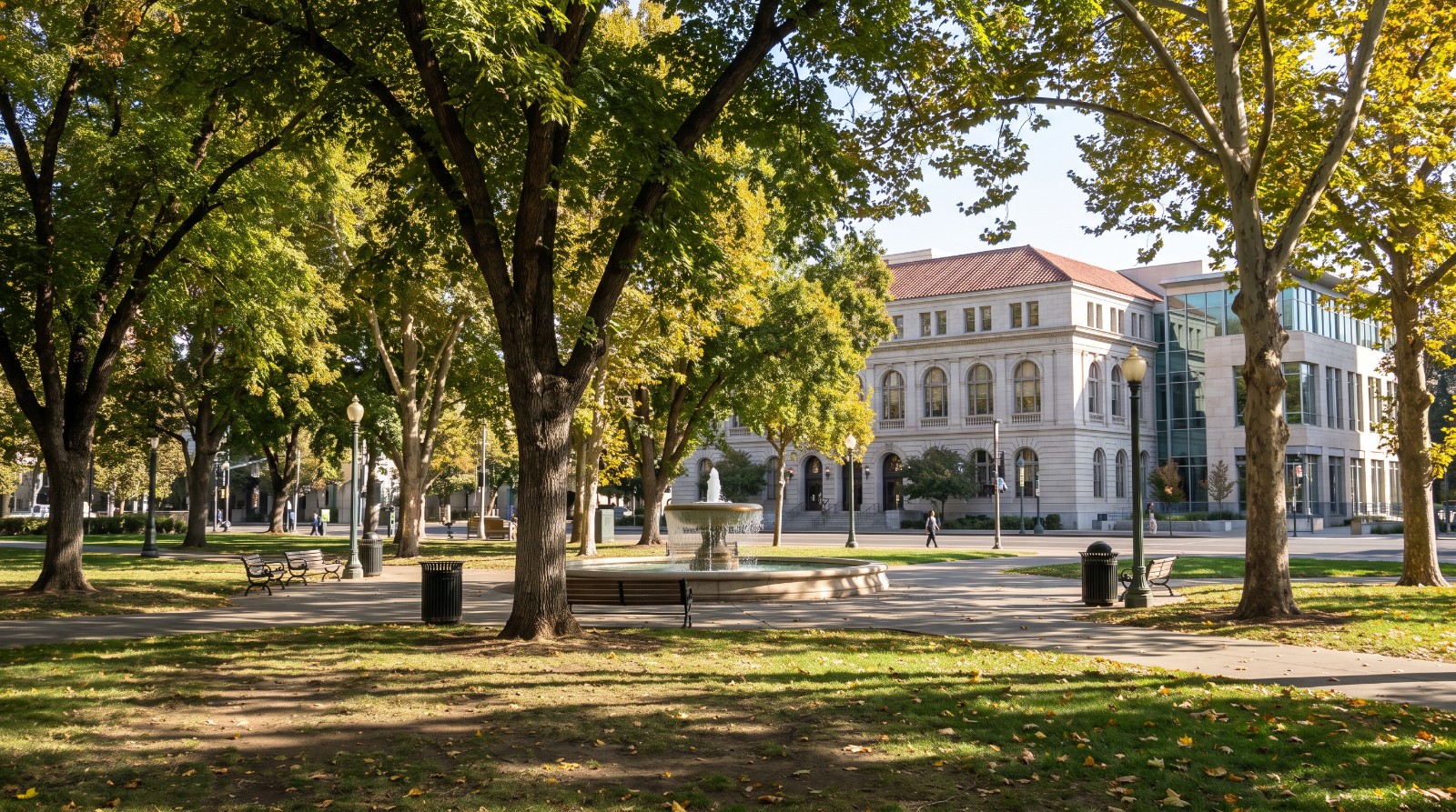 Shaded lawns and paths of Cesar Chavez Plaza in downtown Sacramento, with City Hall behind the trees