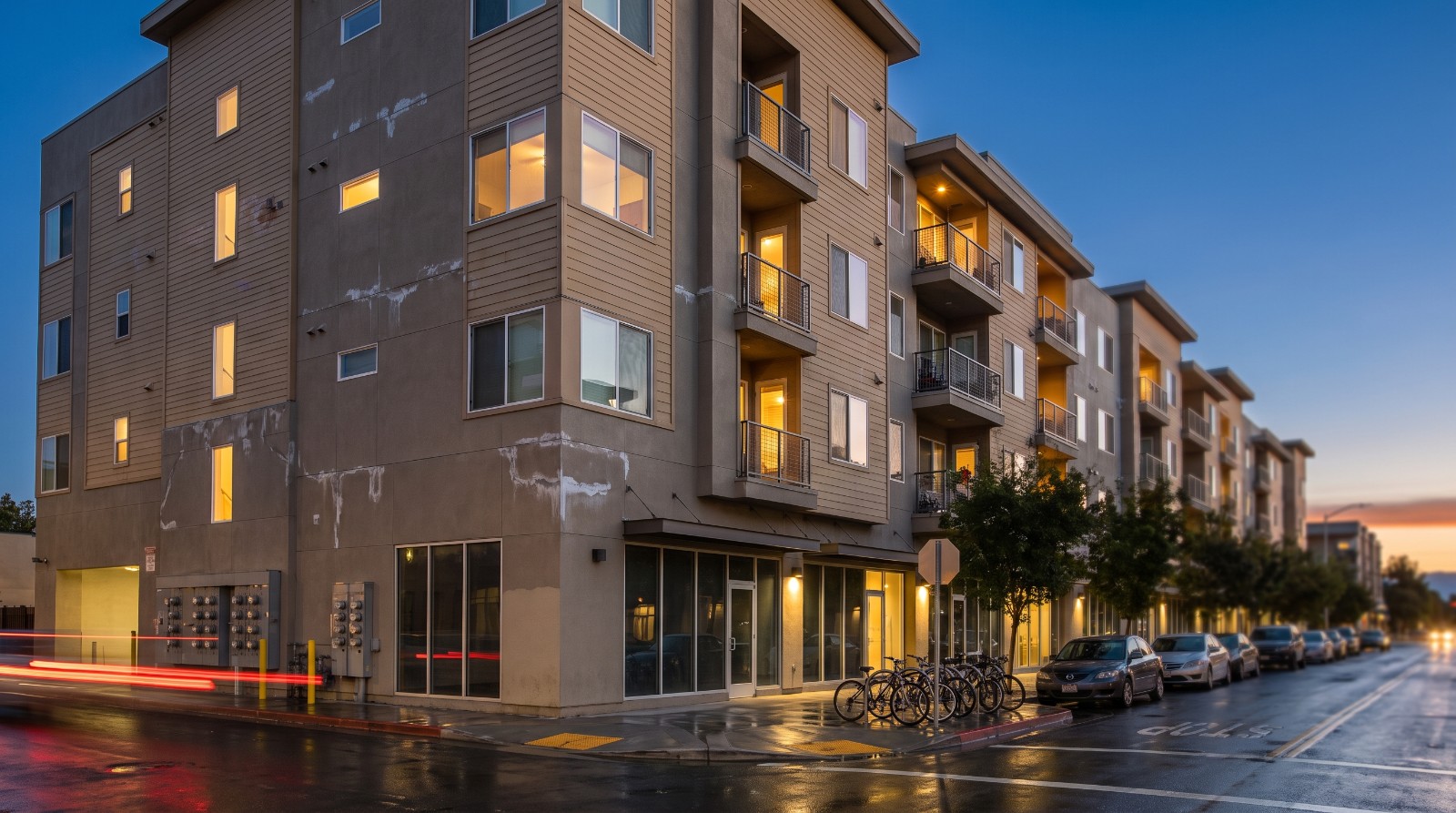 A mid-rise apartment building with lit windows on a downtown San Jose street at dusk, illustrating rising San Jose rents in 2026.