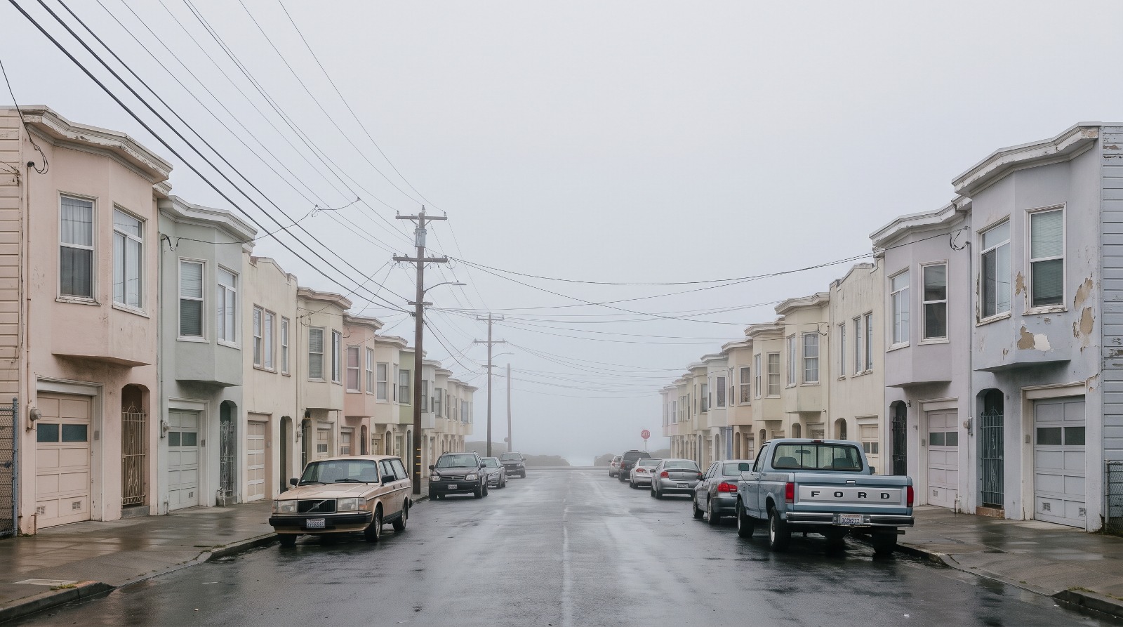 A residential street of pastel stucco houses in the Outer Sunset district of San Francisco with coastal fog at the ocean end