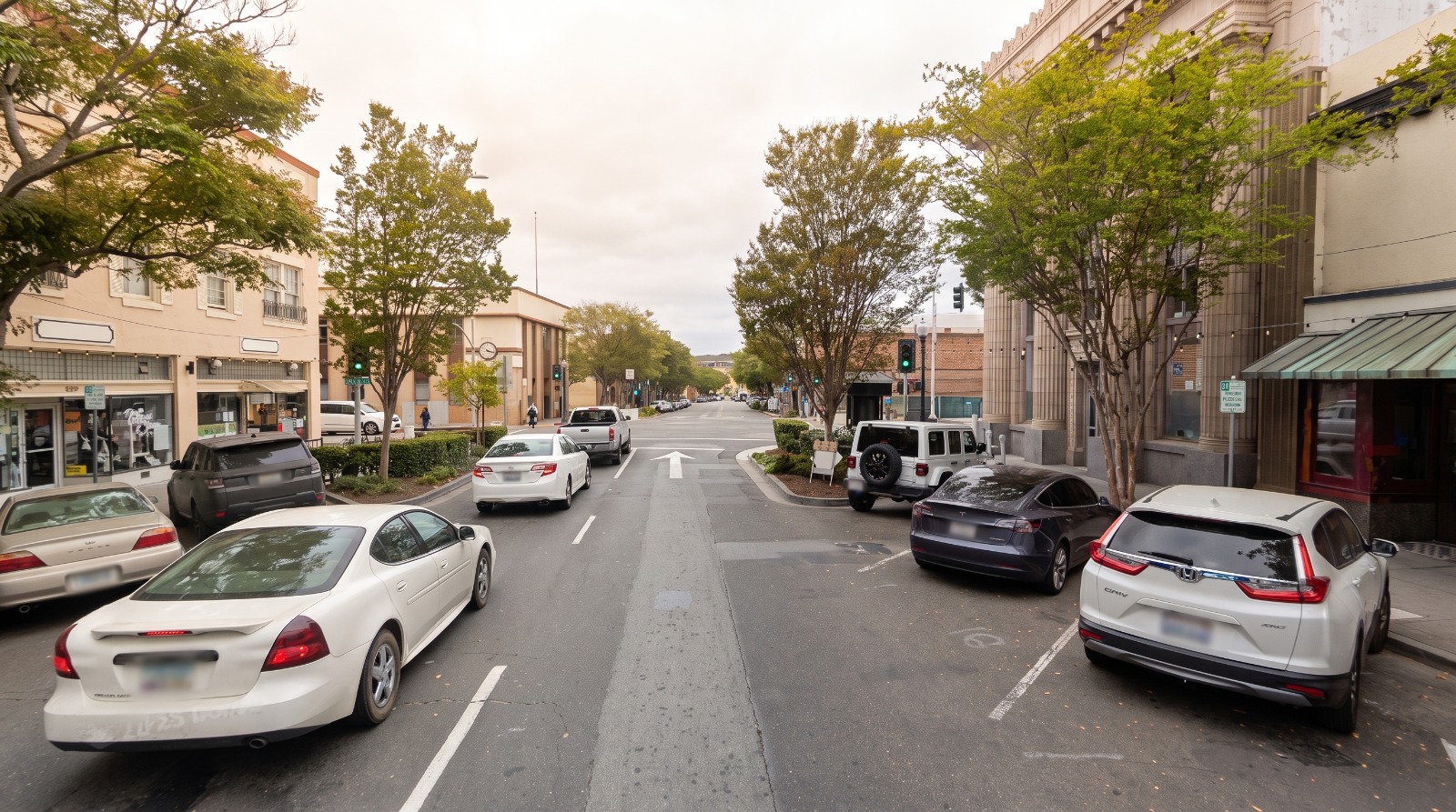 B Street in downtown Hayward lined with two- and three-story storefronts and street trees, looking toward the BART station