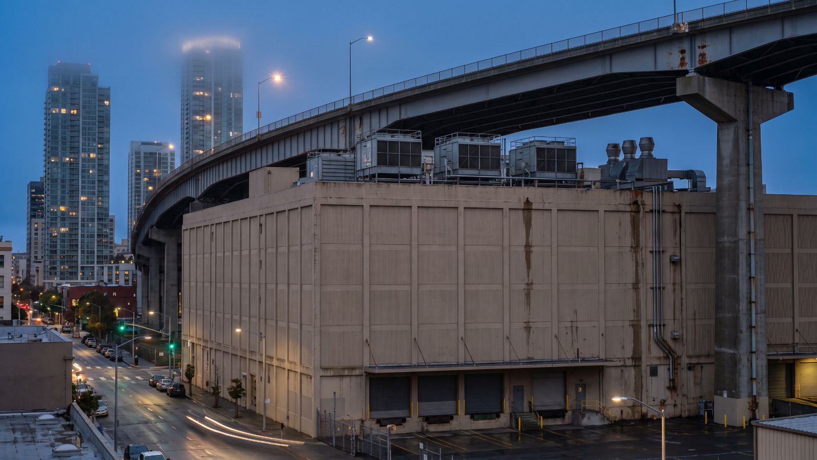 A windowless concrete building with rooftop cooling units under the Bay Bridge approach in Rincon Hill, the kind of site where San Francisco data centers hide.